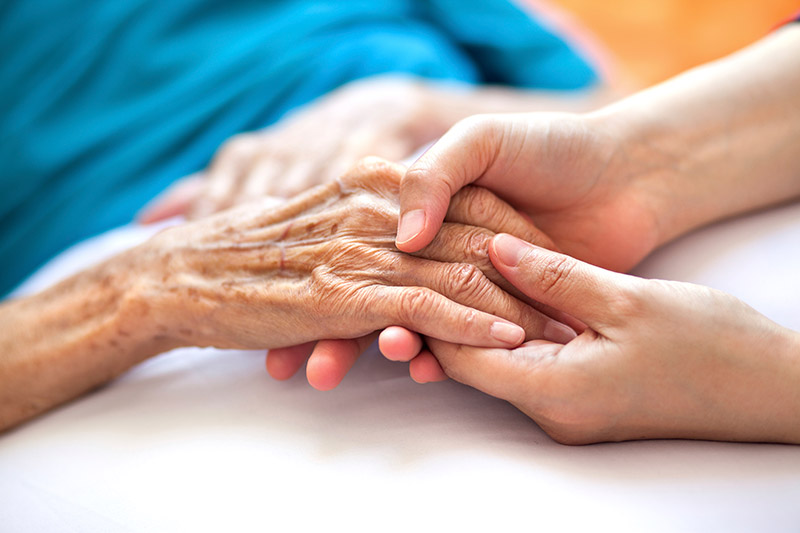 Photo of person holding the hand of a senior person